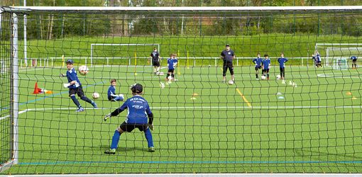 Kinder-Fußballtraining mit Trainer, Blick von hinter dem Tornetz